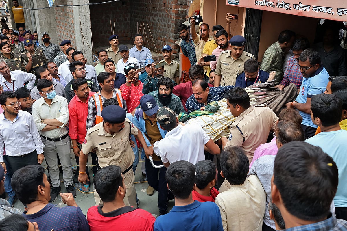 Rescue and security personnel carry a devotee on a stretcher who was injured after the floor covering a stepwell collapsed at a temple in Indore on 30 March 2023.