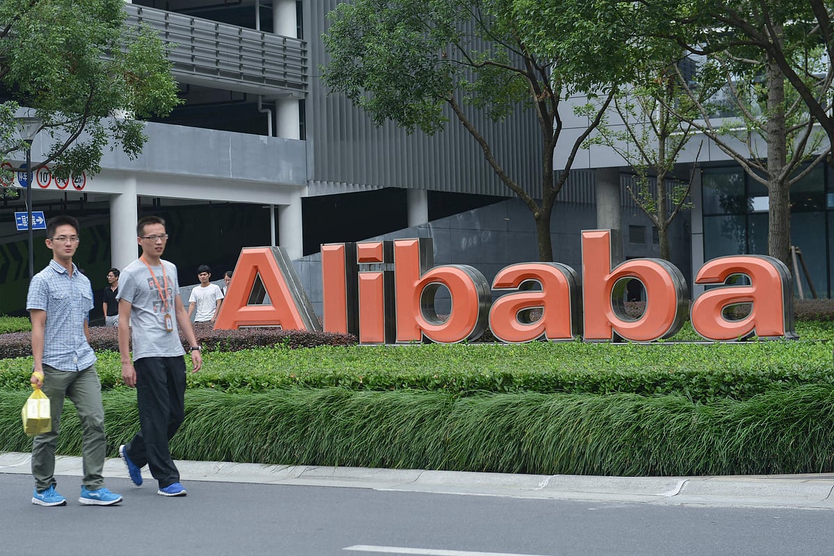 This file photo taken on 27 May, 2022 shows staff members walking past the logo of Chinese e-commerce giant Alibaba at its headquarters in Hangzhou, in China's eastern Zhejiang province. Alibaba announced on 28 March, 2023, that it would split into six individual business groups in one of the most significant overhauls of a leading Chinese tech firm to date.