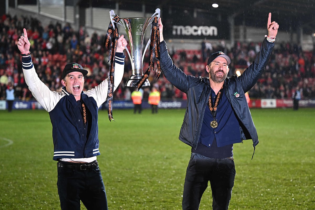 US actors and Wrexham owner Rob McElhenney and Ryan Reynolds celebrate on the pitch with the National League trophy after the match between Wrexham and Boreham Wood at the Racecourse Ground Stadium in Wrexham, Wales on 22 April 2023