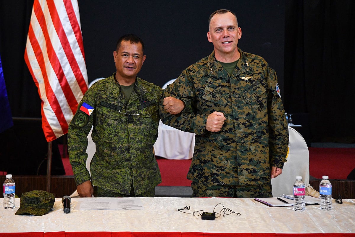 Philippine exercise director Major General Marvin Licudin (L) and US exercise director representative Major General Eric Austin (R) link arms during the opening ceremony of the 'Balikatan' joint military exercise at the military headquarters in Quezon City, suburban Manila on 11 April, 2023