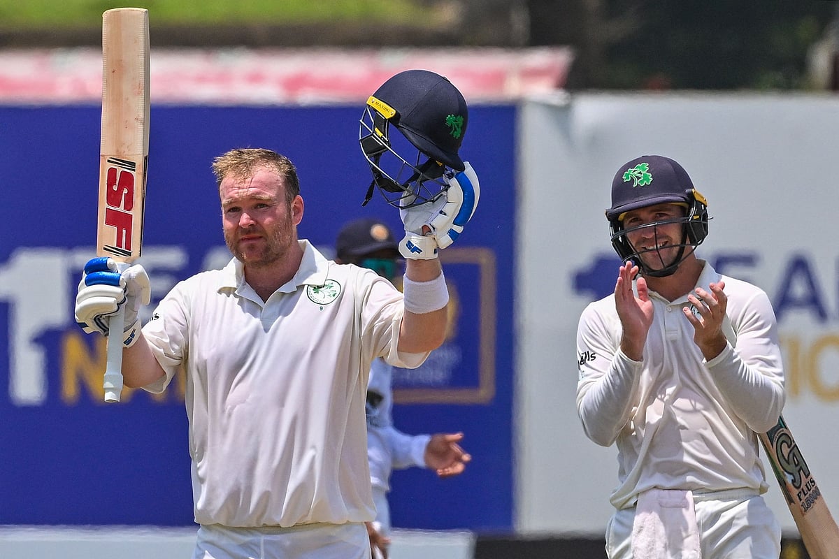 Ireland's Paul Stirling celebrates after scoring a century as his teammate Curtis Campher applauses during the second day of the second and final Test between Sri Lanka and Ireland at the Galle International Cricket Stadium in Galle on 25 April 2023