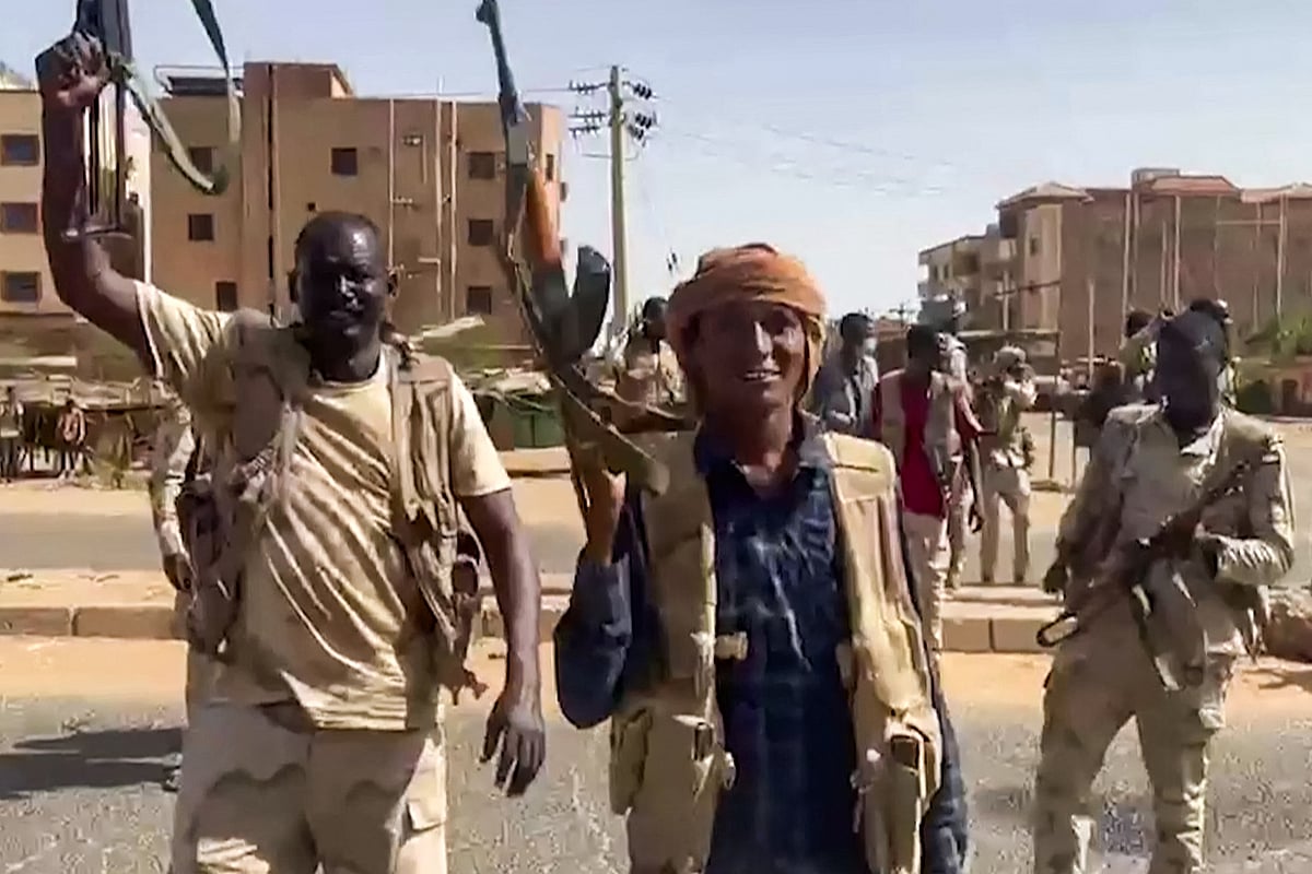 In this image grab taken from handout video footage released by the Sudanese paramilitary Rapid Support Forces (RSF) on 23 April 2023, fighters wave assault rifles as they cross a street in the East Nile district of greater Khartoum
