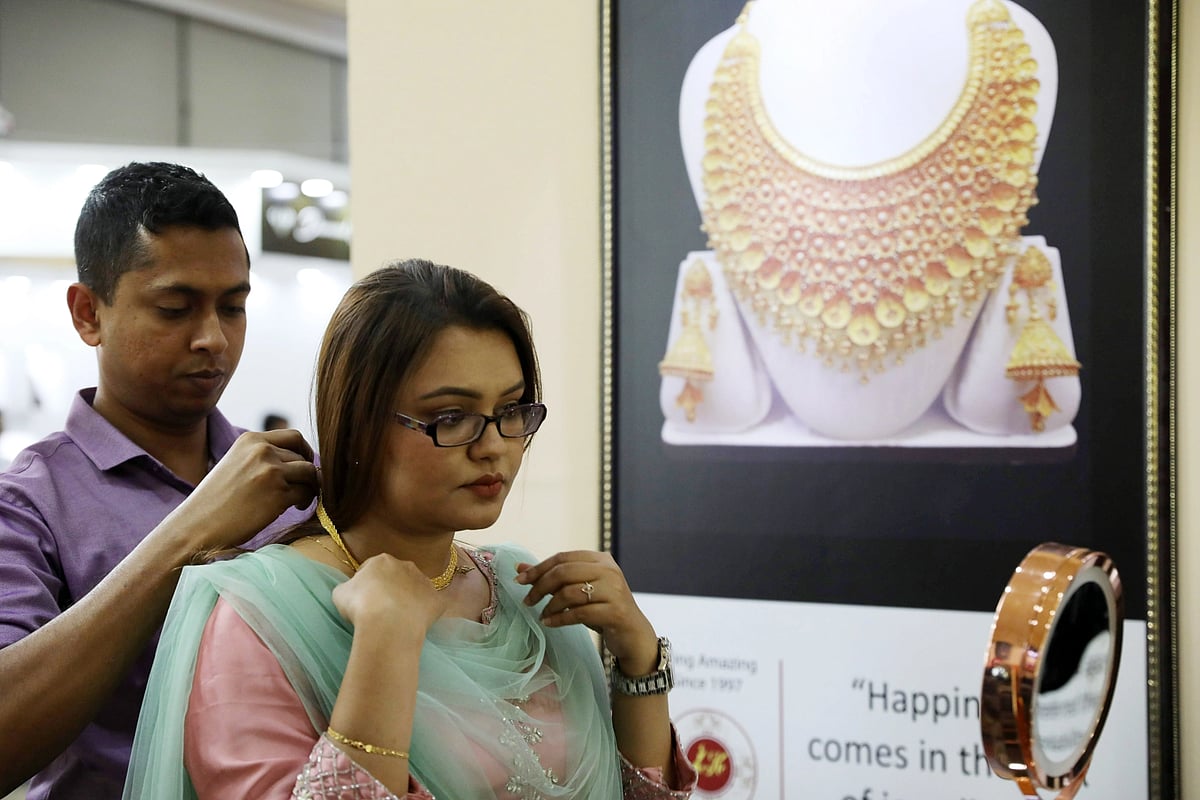 A salesman helps a woman wear a gold chain at a stall of Bangladesh Jewellery Expo-2022 at Bashundhara International Convention Centre in Dhaka on 17 March 2022.