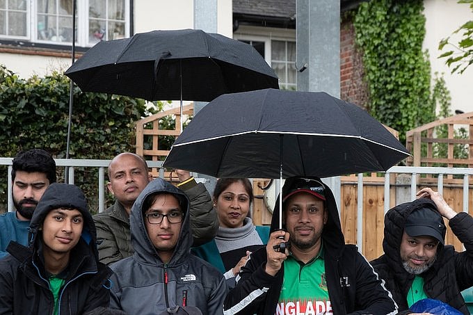Bangladesh fans using umbrellas and wearing raincoats to try save themselves from rain while waiting for the first ODI between Bangladesh and Ireland in Chelmsford, England to resume