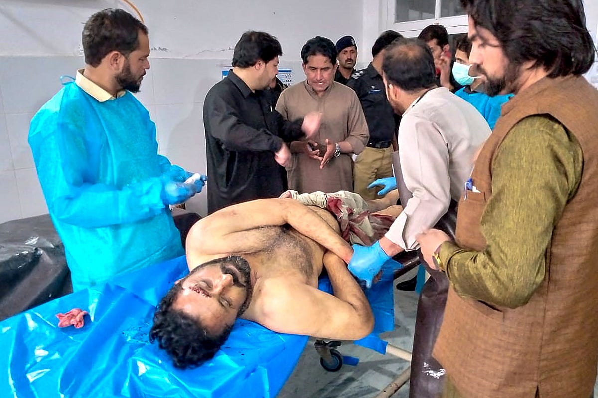 This handout photograph taken and released by the Pakistan's Office of Assistant Commissioner Parachinar district Kurram, on 4 May, 2023 shows a paramedic (L) treating a victim of the sectarian violence inside a school in Parachinar. Five teachers and two labourers were gunned down on 4 May at a school in northwest Pakistan, in an attack linked to Sunni-Shiite sectarian tensions, police and government officials said.