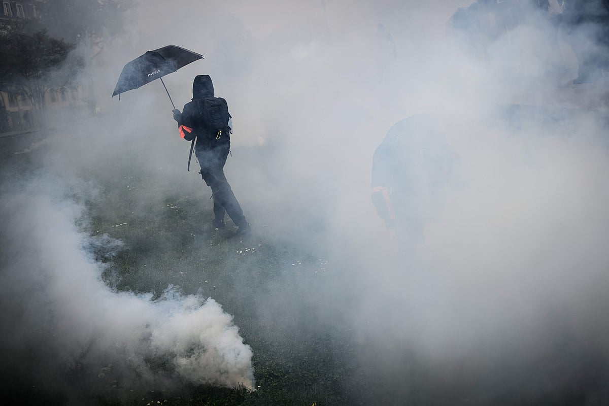 A protestor stands in clouds of tear gas amid clashes with riot police during a demonstration on May Day (Labour Day), to mark the international day of workers, more than a month after the government pushed an unpopular pensions reform act through parliament, in Nantes, northwestern France, on May 1, 2023