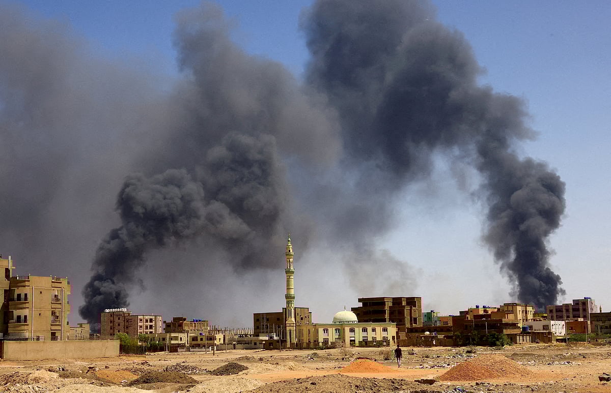 A man walks while smoke rises above buildings after aerial bombardment, during clashes between the paramilitary Rapid Support Forces and the army in Khartoum North, Sudan, May 1, 2023