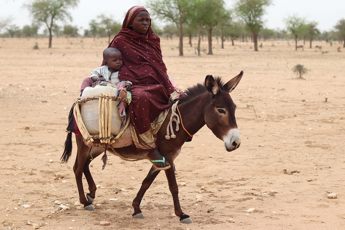 Sudanese refugees cross into Chad riding a donkey near Koufroun, Echbara, on 1st May, 2023. Hundreds of Sudanese, most of them women and children, each day cross a small, dry stream to find safety in neighbouring Chad. At least 20,000 people had found refuge at a makeshift camp in the Chadian border village of Koufroun, according to the United Nations refugee agency UNCHR, which manages their influx along with other UN agencies.