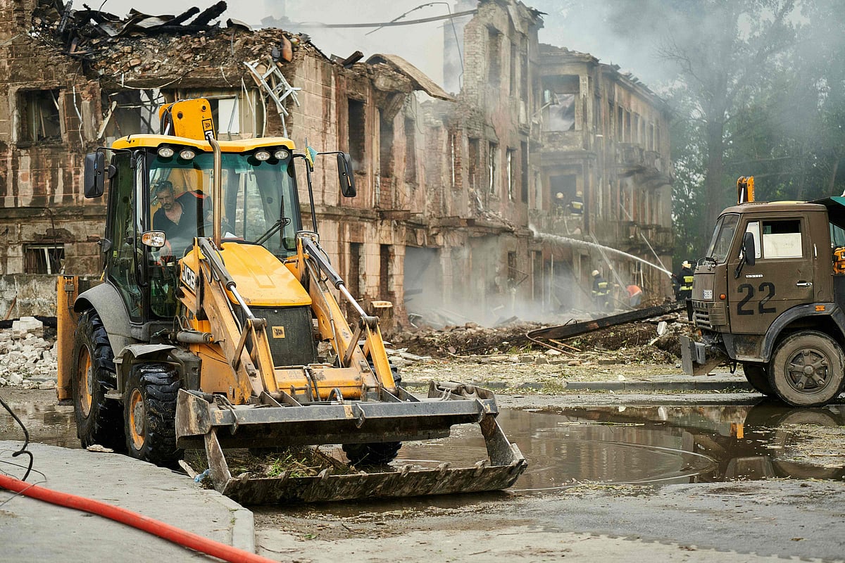 Workers clear debries as firefighters extinguish a fire at a medical facility, destroyed by a missile strike, in the city of Dnipro on May 26, 2023, amid the Russian invasion of Ukraine