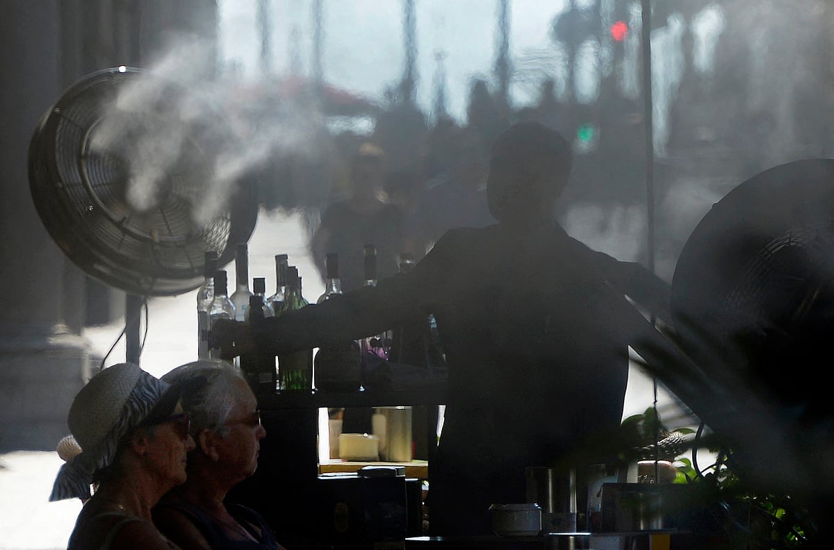 A fan placed on a terrace of a bar sprays water to cool off clients during a heatwave in Madrid on 28 June, 2015. Extreme weather events such as heat waves and floods have cost some 195,000 lives and nearly 560 billion euros in Europe since 1980, according to the European Environment Agency (EEA), which called to take new measures against the climate change