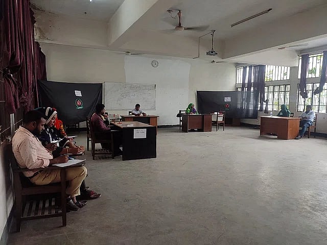 Election officials sit idle inside a voting centre at the Government Homeopathic Medical College in Bhashantek, Dhaka on 17 July 2023