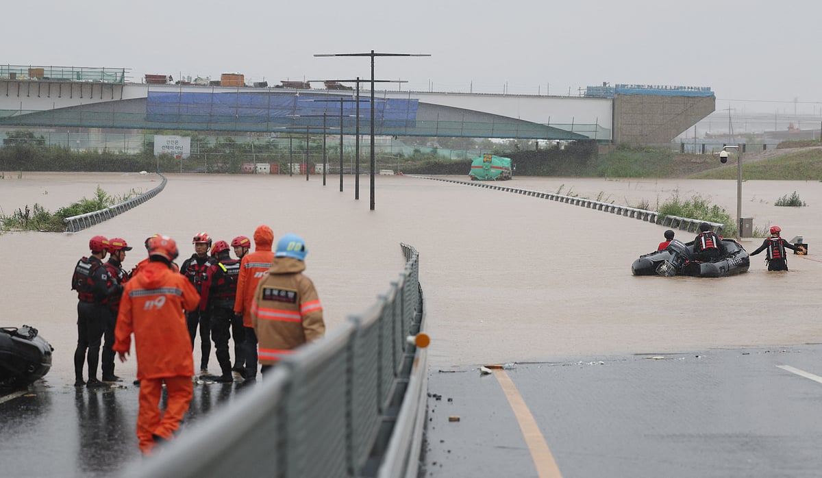 South Korean emergency workers search for survivors on a flooded road leading to an underground tunnel where some 19 cars were trapped by flood waters after heavy rains in Cheongju on 15 July, 2023.