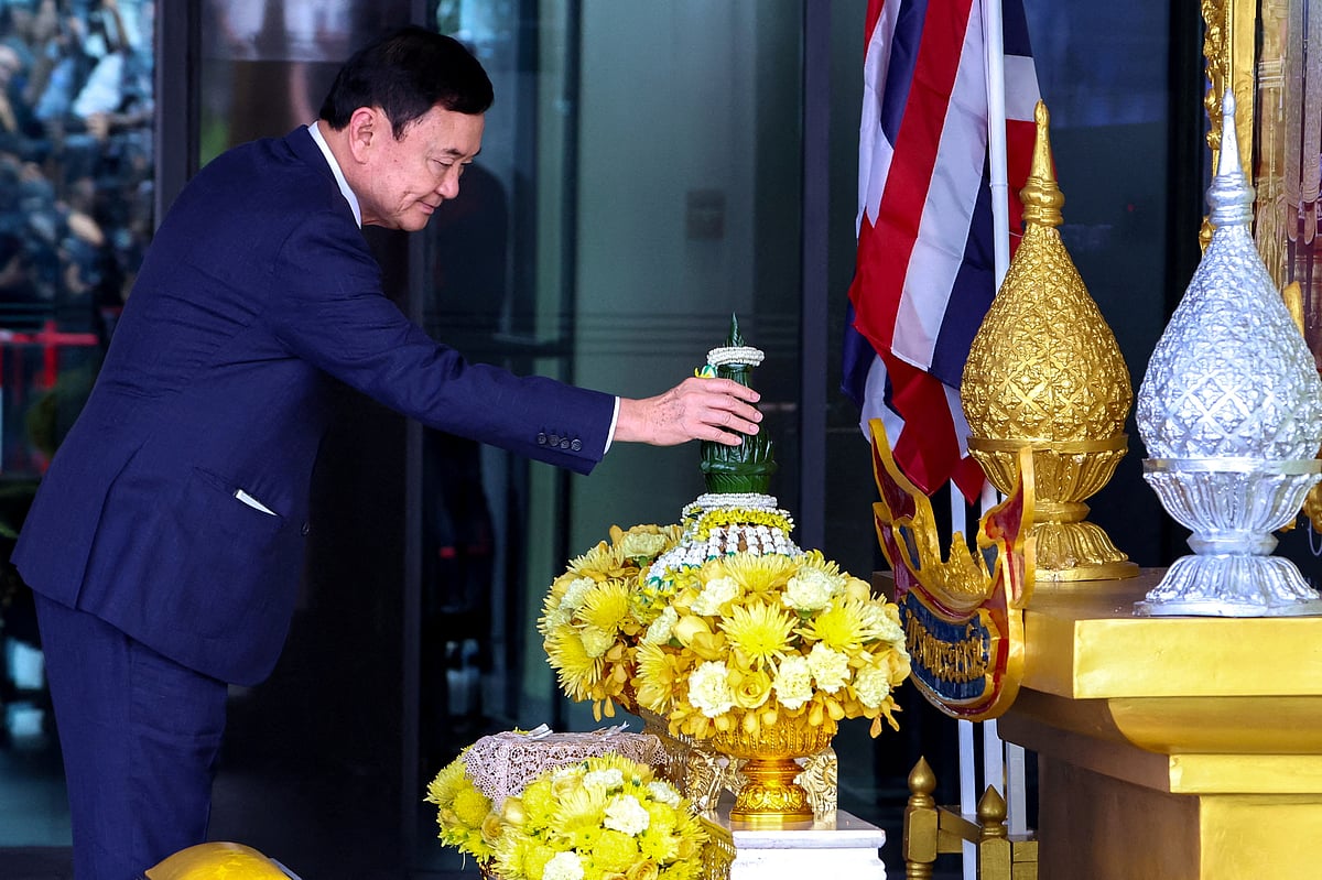 Former Thai Prime Minister Thaksin Shinawatra, who is expected to be arrested upon his return as he ends almost two decades of self-imposed exile, pays his respects to a portrait of Thailand's King Maha Vajiralongkorn and Queen Suthida at Don Mueang airport in Bangkok, Thailand August 22, 2023