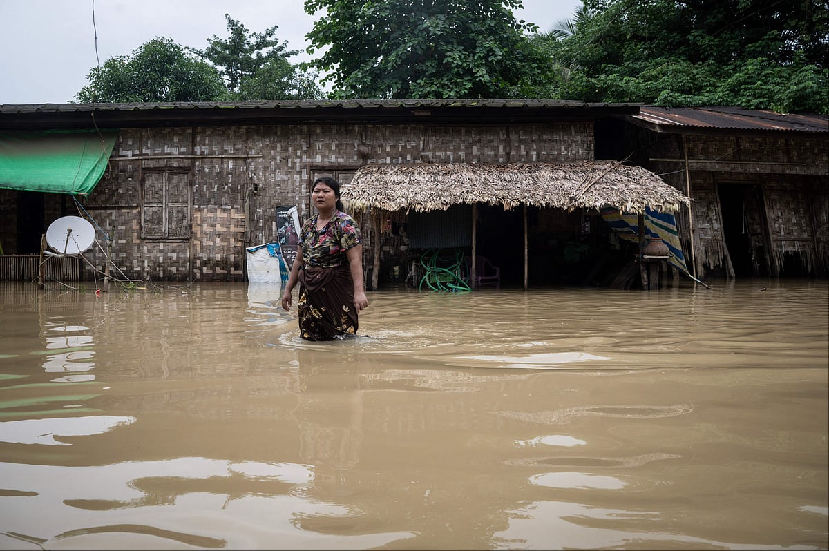 A woman wades through a flooded street in Bago township in Myanmar's Bago region on 12 August, 2023.