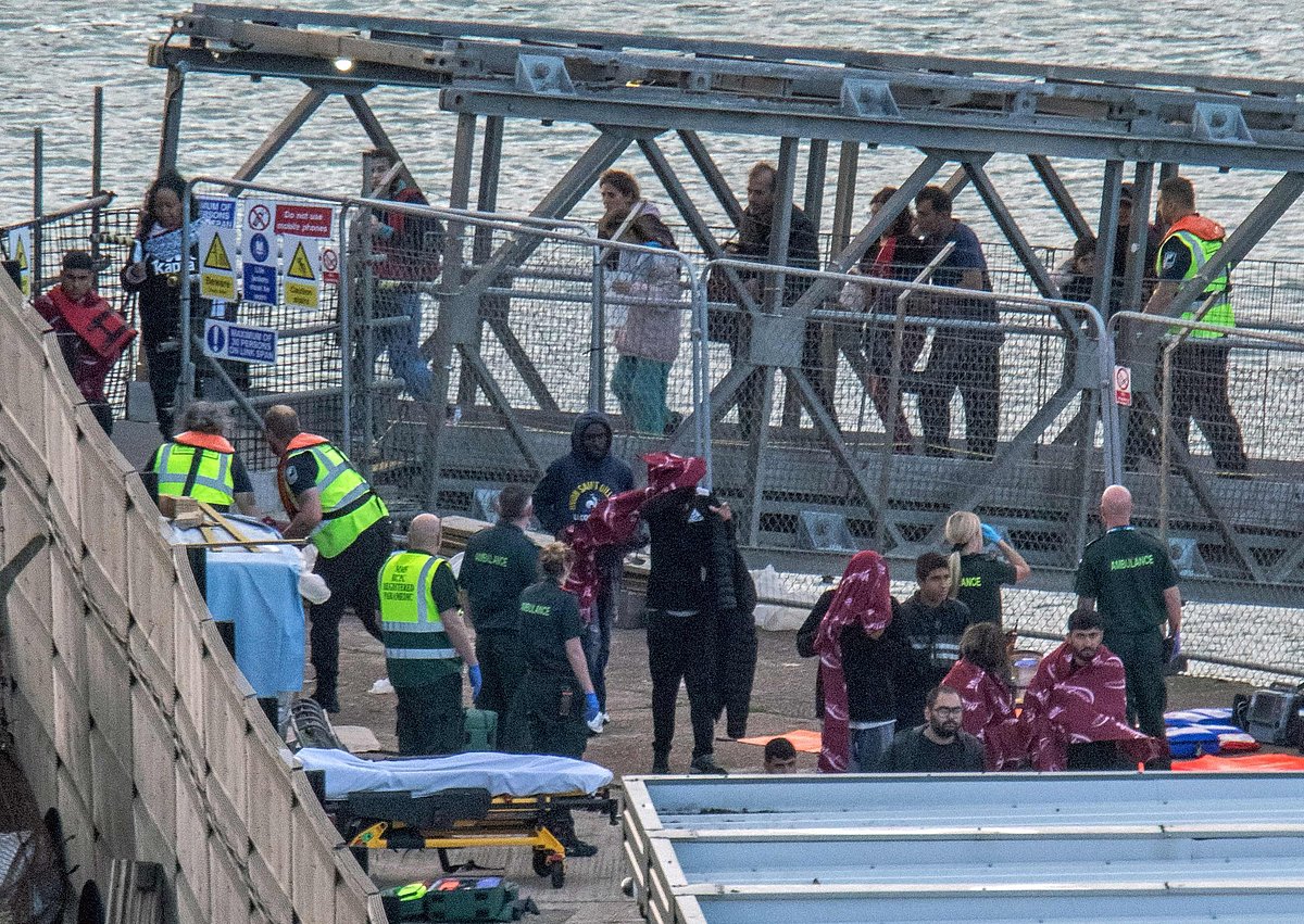 Paramedics wait to tend to assist migrants picked up at sea while attempting to cross the English Channel, after disembarking from a UK Royal National Lifeboat Institution (RNLI) lifeboat at the Marina in Dover, southeast England, on August 12, 2023
