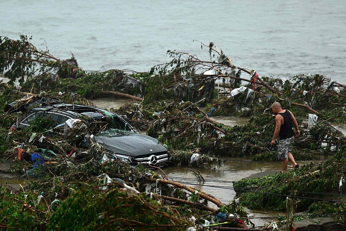 A man looks at a damaged car following heavy rains in Fangshan district in Beijing on 1 August, 2023