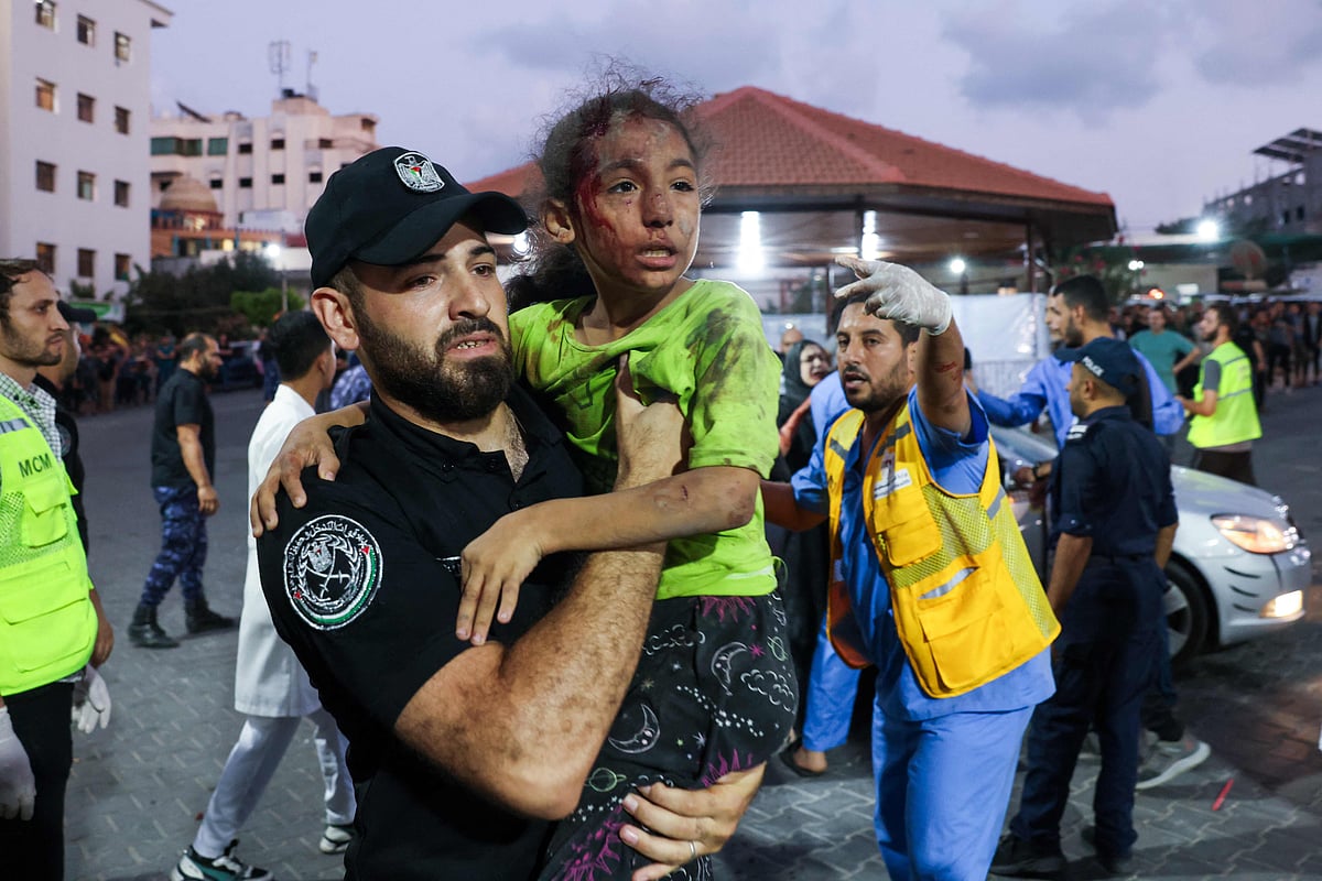 A member of the Palestinian security forces carries a child, wounded by Israeli airstrikes, into Al-Shifa hospital in Gaza City on 11 October, 2023