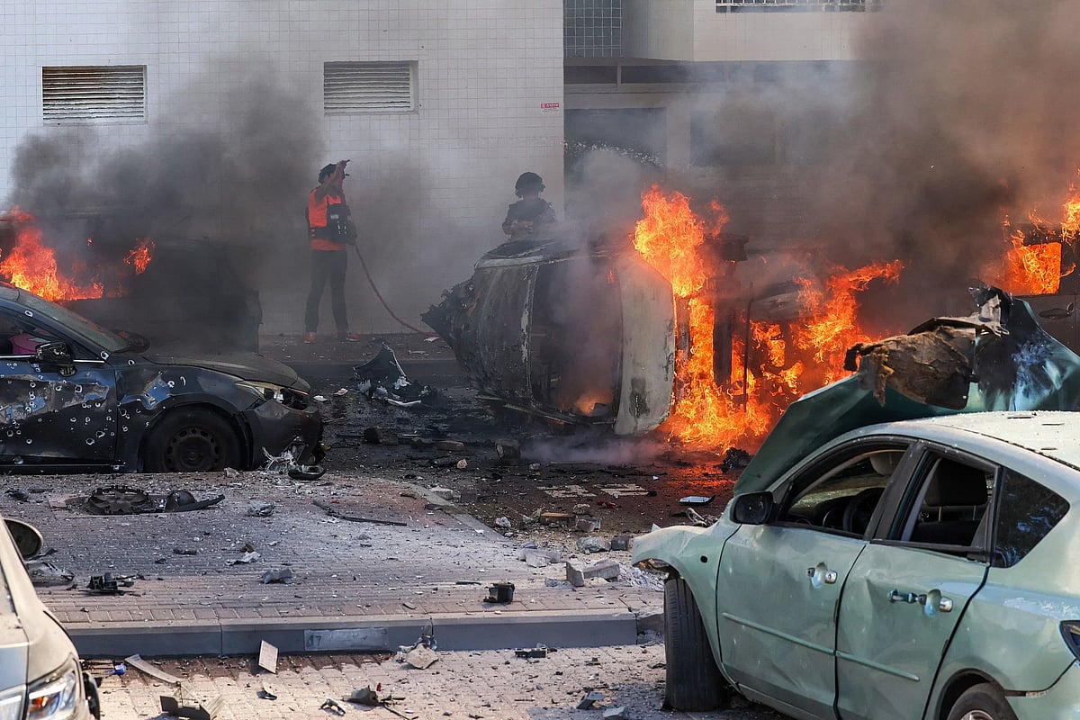 A member of the Israeli security forces stood near burning cars following a rocket attack from the Gaza Strip in Ashkelon, southern Israel, on 7 October, 2023.