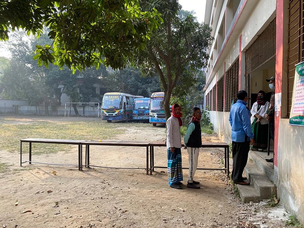 Photo shows three men waiting in line to cast vote during the 12th parliamentary election at Dhaka Government Muslim High School in Lakshmi Bazaar, Dhaka on 7 January 2024.