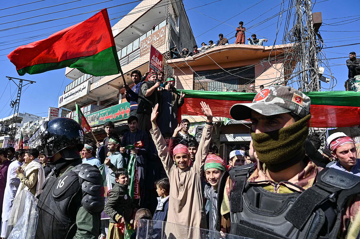 Frontier Constable personel stand guard as people cheer outside a polling station during Pakistan's national election in Islamabad on 8 February, 2024.