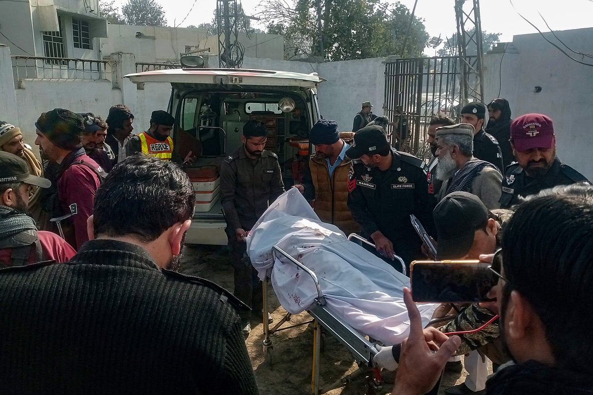 Graphic content / Policemen shift the body of a colleague who was killed in an attack on a police station, at a hospital in Dera Ismail Khan on February 5, 2024