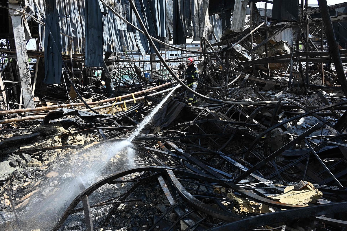 An employee of the State Emergency Service of Ukraine sprays water on debris in a hardware supermarket in Kharkiv destroyed by a Russian strike, on 26 May, 2024, amid the Russian invasion in Ukraine
