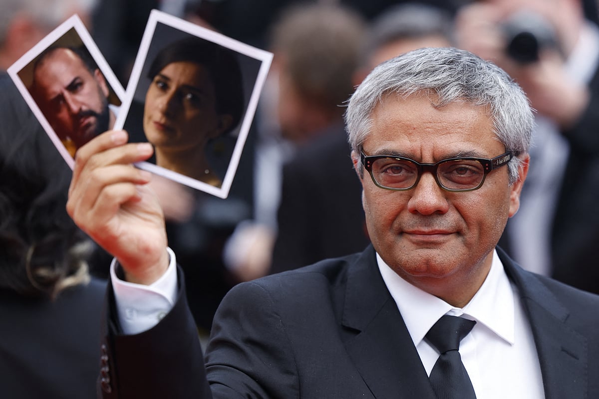 Director Mohammad Rasoulof holds pictures of cast members iranian actors Missagh Zareh and Soheila Golestani as he leaves following the screening of the film 'The Seed of the Sacred Fig' (Les Graines du figuier sauvage) in competition at the 77th Cannes Film Festival in Cannes, France, 24  May, 2024.