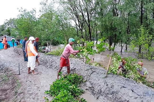 Water enters locality after overflowing the low embankments due to the cyclone Remal induced water surge in the river. The local people are repairing the embankments as ebb begins in the river. The picture was taken from Shakbaria river embankment in Koyra upazila of Khulna on Monday afternoon.