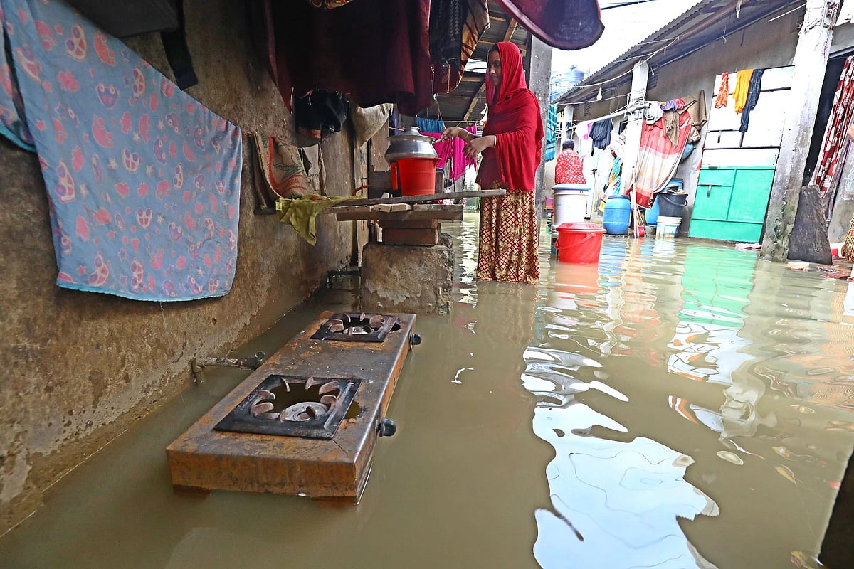 A woman cooks in knee-deep water at Machimpur in Sylhet on 20 June, 2024.