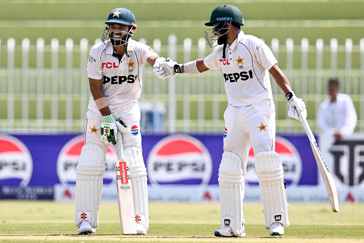 Pakistan’s Mohammad Rizwan (L) celebrates with Saud Shakeel after scoring a half-century (50 runs) during the second day of the first Test cricket match between Pakistan and Bangladesh at the Rawalpindi Cricket Stadium in Rawalpindi on 22 August 2024