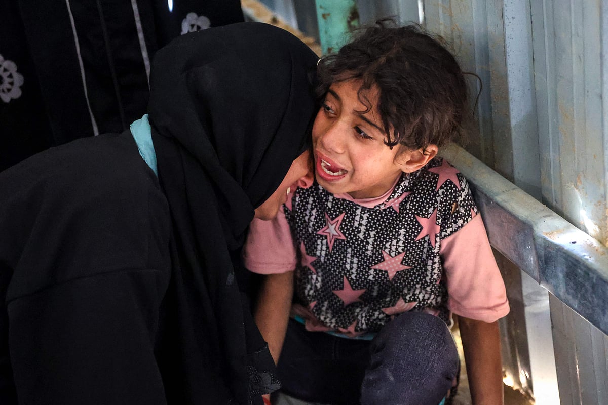 A woman and child mourn next to the bodies of loved ones killed during an Israeli strike that targeted a UN clinic in the Jabalia camp for Palestinian refugees, at the Indonesian Hospital in Beit Lahia in the northern Gaza Strip on 2 April, 2025.