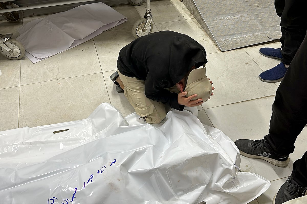 A Palestinian man mourns over the shrouded body of a loved one killed during Israeli bombardment, at the Nasser Medical Complex in Khan Yunis in the southern Gaza Strip on 8 April 2025.