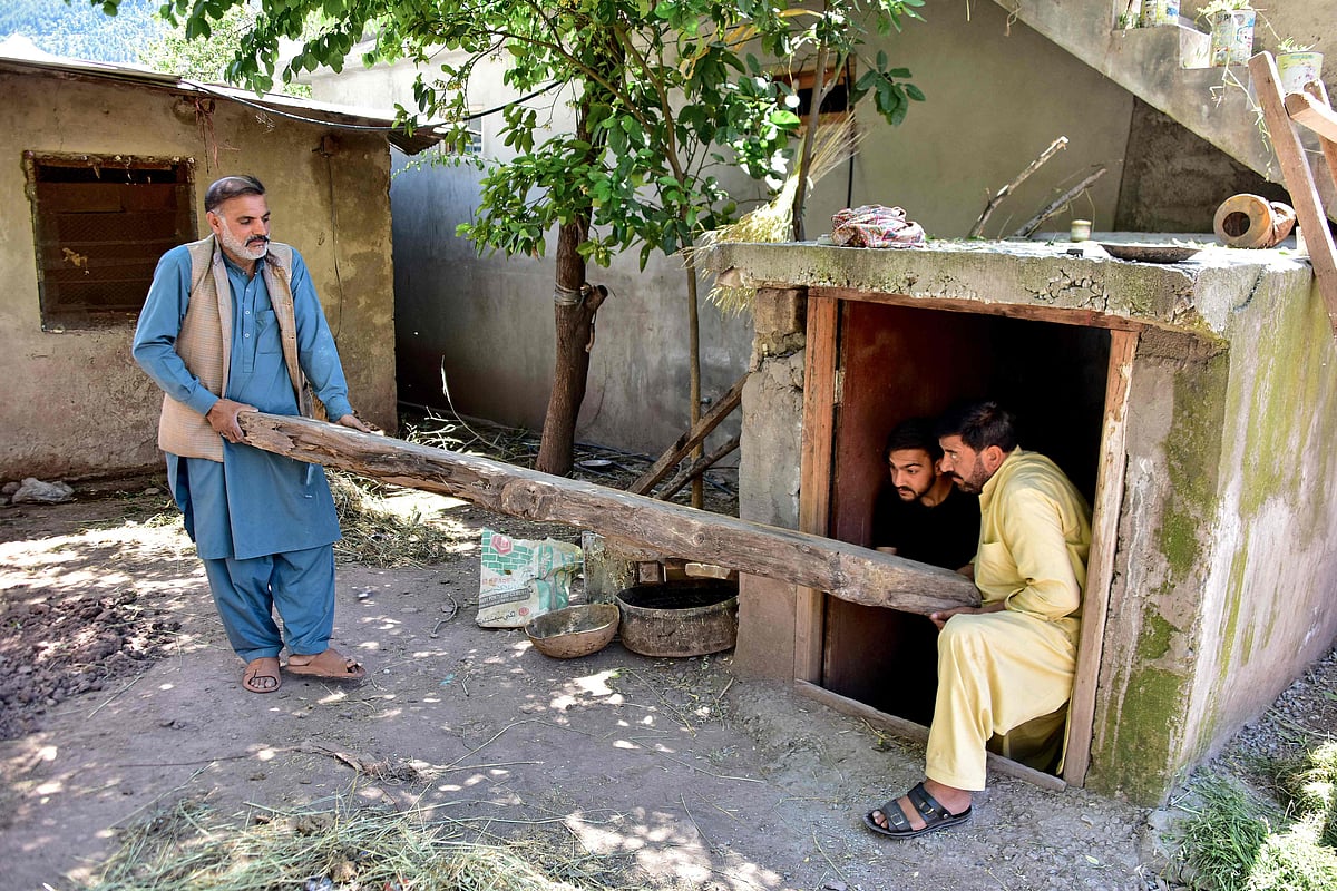 This photograph taken on April 28, 2025 shows Shabbir Awan (L) with his relatives clearing a wooden log from an underground bunker in the Chakothi village of Pakistan-administered Kashmir, about 3kms from the Line of Control (LoC)