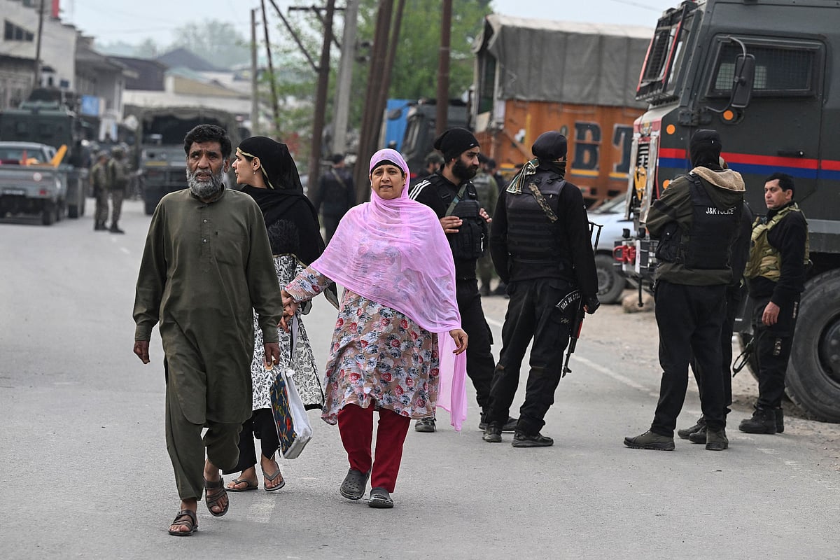 Indian security personnel stand guard as people walk along a road in Wuyan near Indian-administered Kashmir’s main city of Srinagar on 7 May 2025.