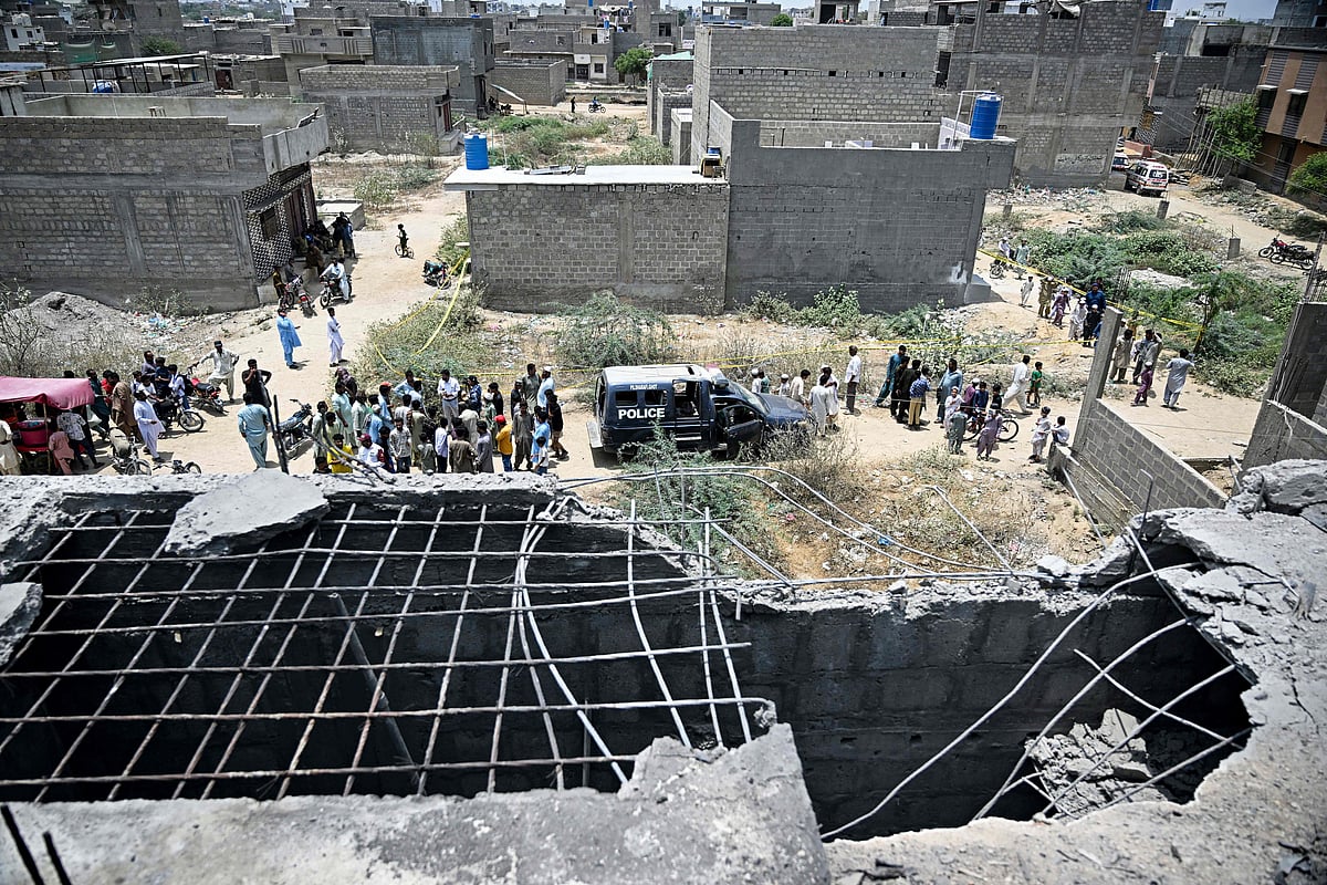 Residents gather as police personnel inspect the site where an alleged drone was shot down in Karachi on 8 May, 2025.