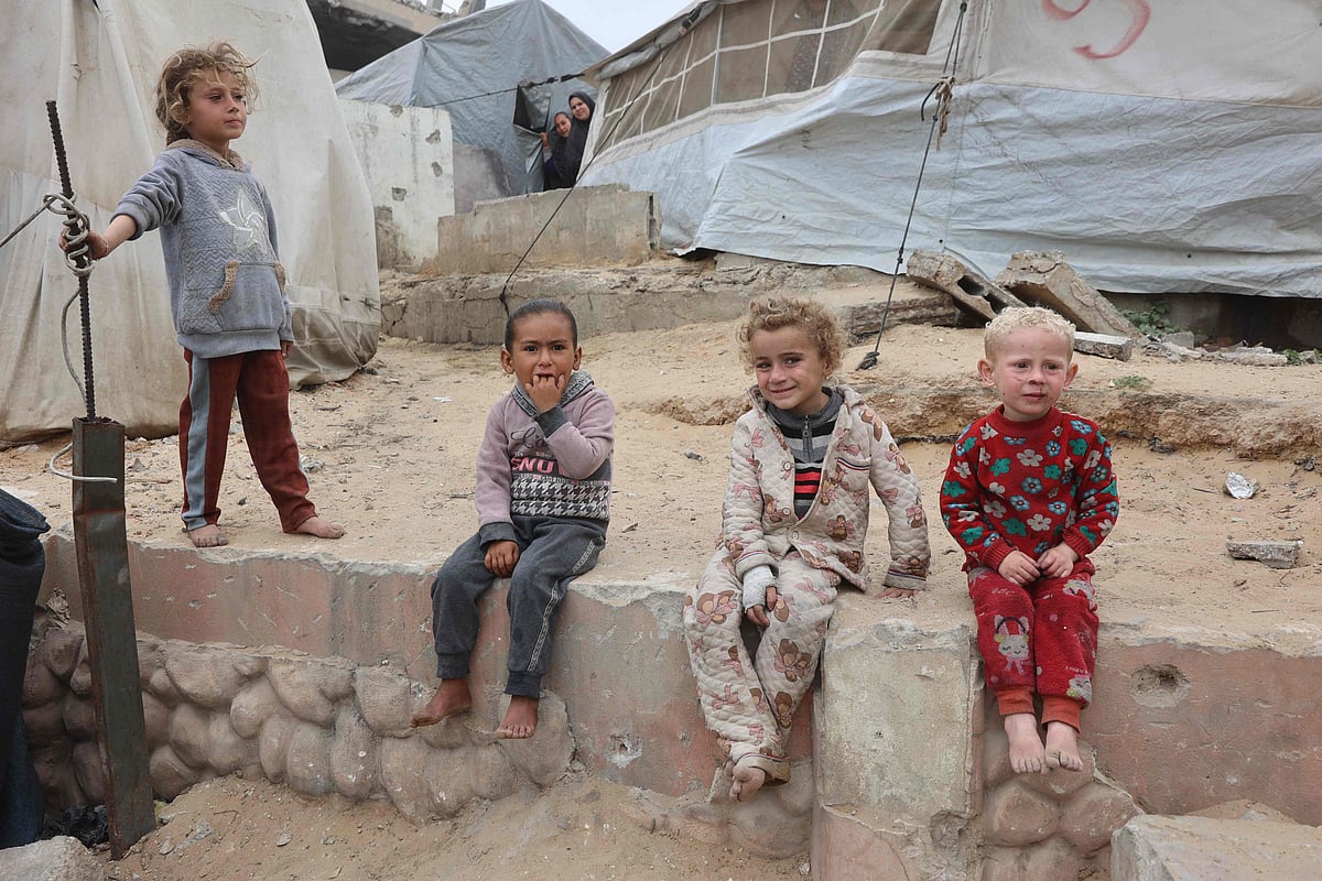 Palestinian children sit by tents at a makeshift displacement camp set up amid building rubble in Gaza City on 12 May 2025