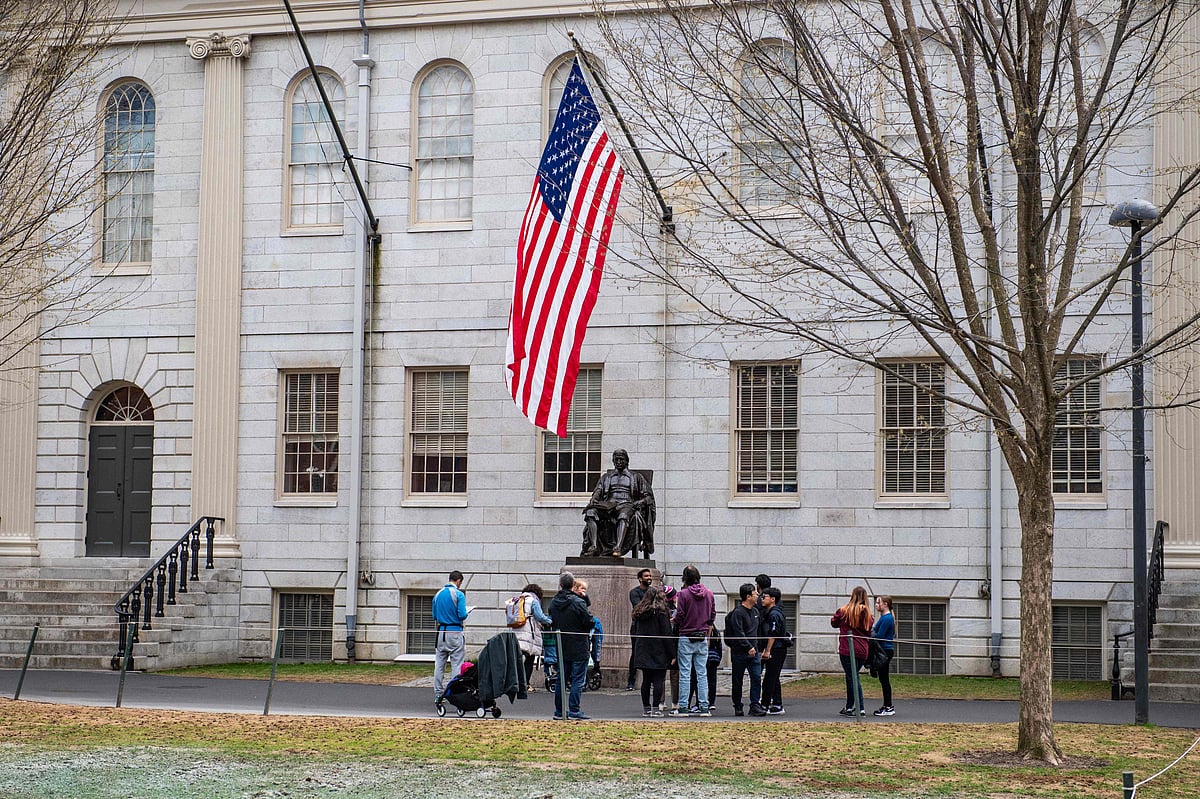 People gather around the John Harvard Statue on the Harvard University campus in Cambridge, Massachussetts, on 15 April 2025