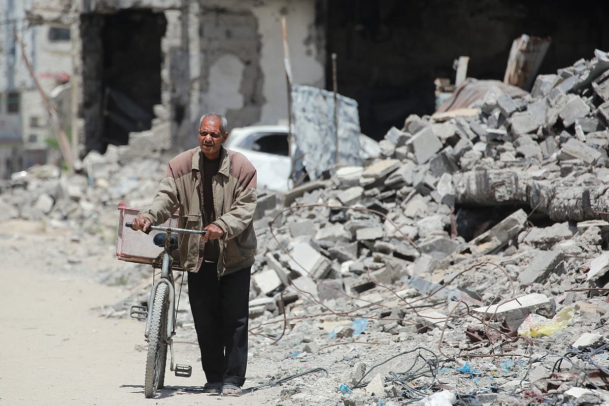 An elderly Palestinian man pushes a bicycle past the rubble of destroyed buildings, in Gaza City, on 20 May 2025, amid the ongoing war between Israel and the Hamas
