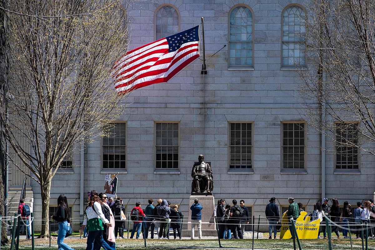 Demonstrators with signs stand around the John Harvard Statue in Harvard Yard following a rally against President Donald Trump’s attacks on Harvard University at Harvard University in Cambridge, Massachusetts on 17 April 2025.