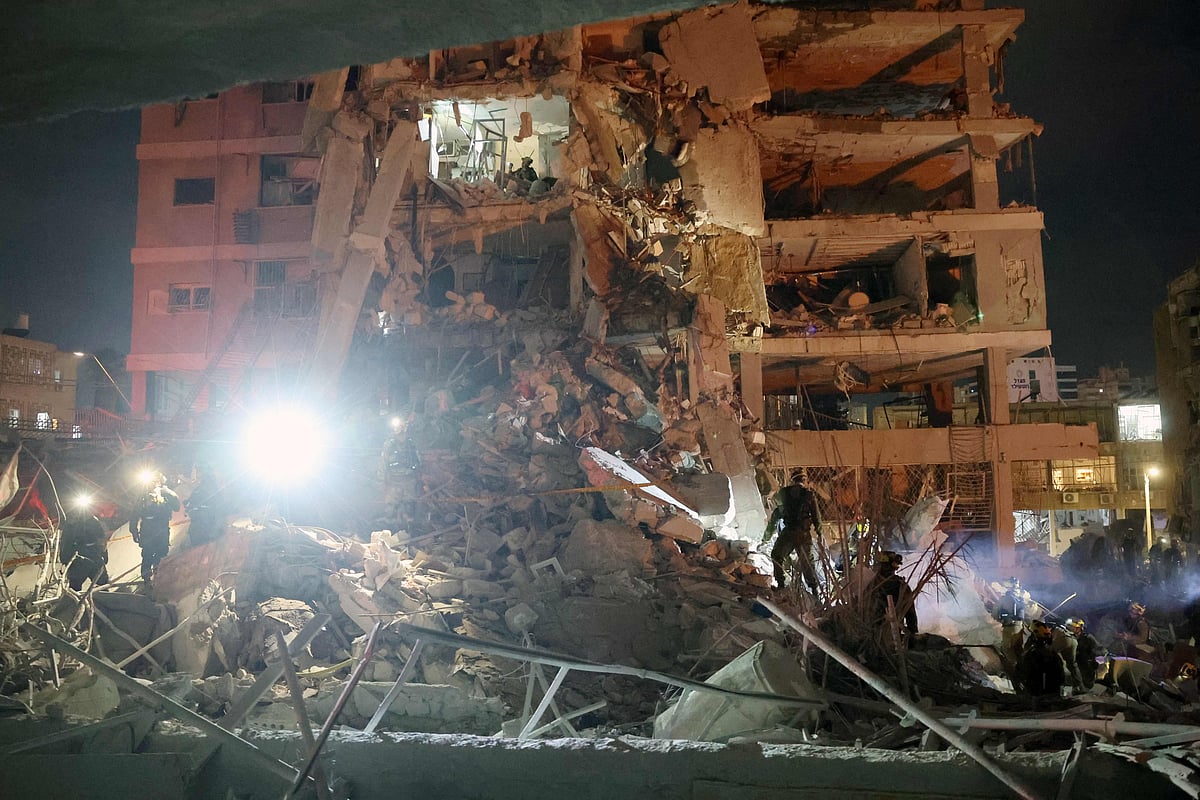 Responders work beside a damaged building following a hit by an Iranian ballistic missile in the Israeli city of Bat Yam, south of Tel Aviv, early on 15 June, 2025.