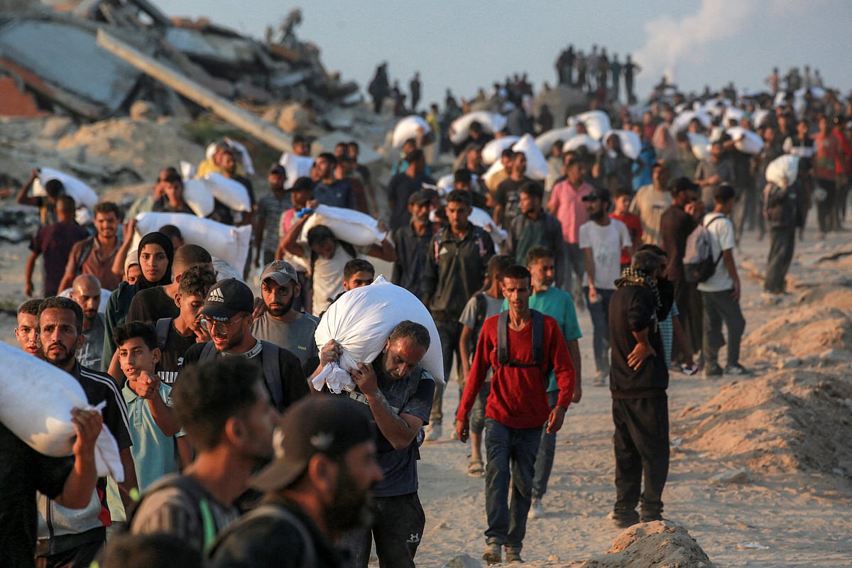 People carrying sacks of flour walk along al-Rashid street in western Jabalia on 17 June, 2025, after humanitarian aid trucks reportedly entered the northern Gaza Strip through the Israeli-controlled Zikim border crossing, amid the ongoing war between Israel and Hamas.