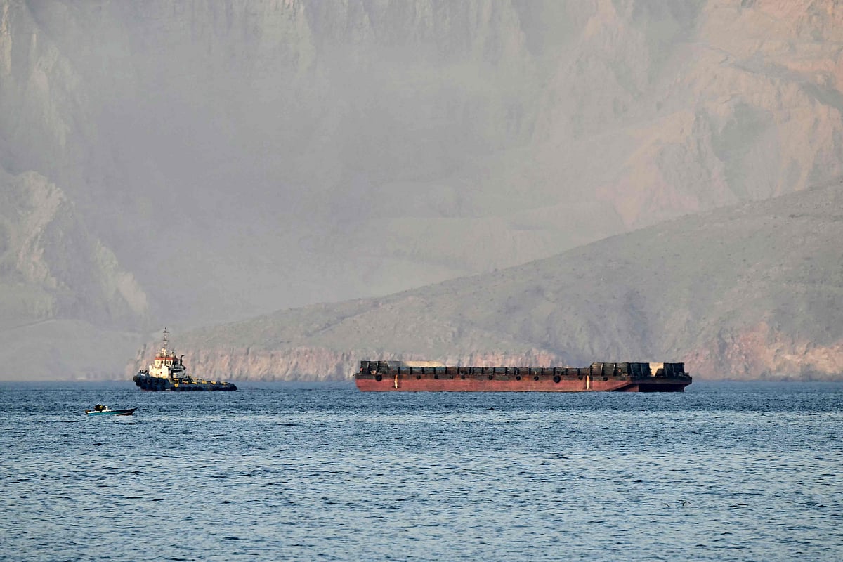 A tug boat tows a barge off the coast of Khasab, on northern Oman’s Musandam Peninsula overlooking the Strait of Hormuz on 24 June 2025