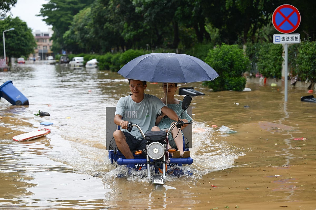 People ride a motorcycle through a flooded street in Zhongshan, China's southern Guangdong province on June 17, 2025