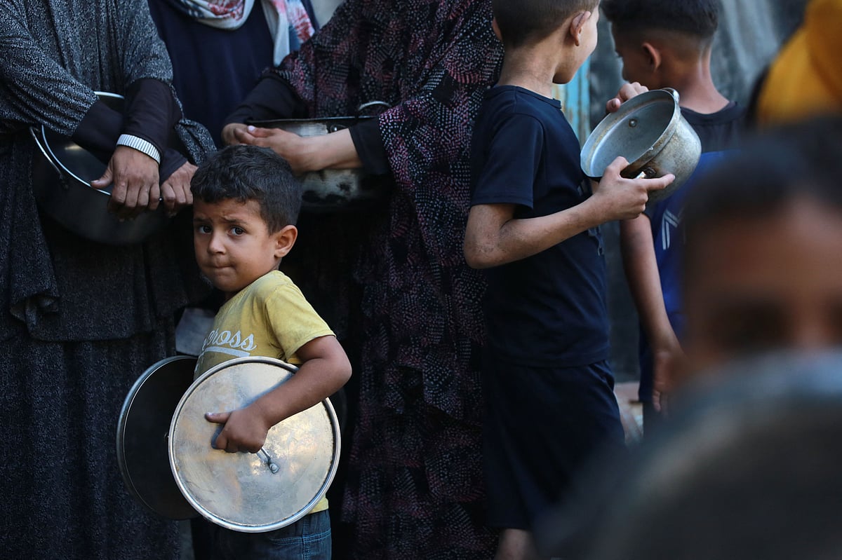 Palestinians line up to receive a hot meal at a food distribution point in Gaza City on 27 June 2025.