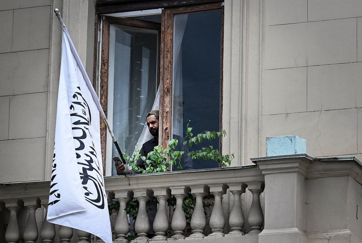 An official uses his smartphone next to the flag of the Islamic Emirate of Afghanistan at the balcony of the Afghan embassy in Moscow on 4 July 2025. Russia became the first country to recognise the Taliban’s rule in Afghanistan. The Taliban swept back to power in 2021 after ousting the foreign-backed government and have imposed an austere version of Islamic law