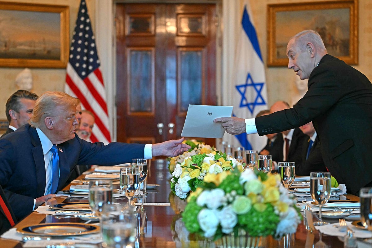 Israeli Prime Minister Benjamin Netanyahu (R) hands over a letter to US President Donald Trump as they meets at the Blue Room of the White House in Washington, DC, on 7 July, 2025