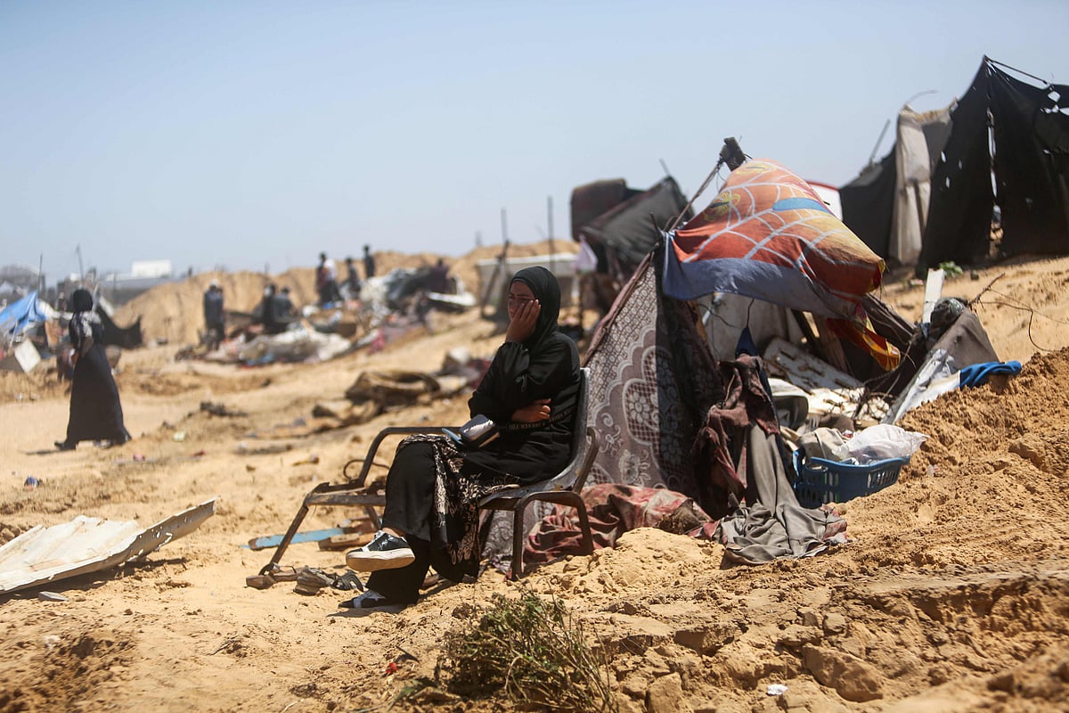 A woman sitting by salvaged belongings looks on as Palestinians inspect the destruction at a makeshift displacement camp following a reported incursion a day earlier by Israeli tanks in the area in Khan Yunis in the southern Gaza strip on 11 July 2025.