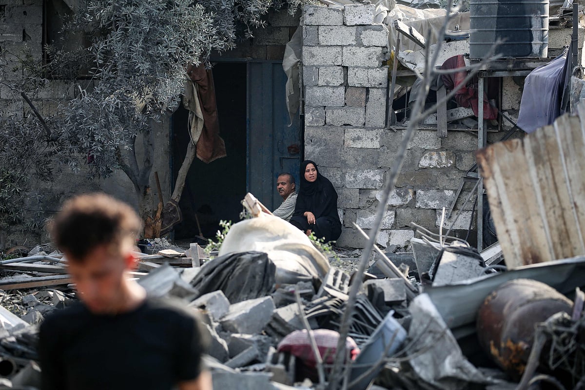 Palestinians sit amid the rubble of a house in the aftermath of an overnight Israeli strike that hit Nuseirat in the central Gaza Strip on 13 July, 2025.