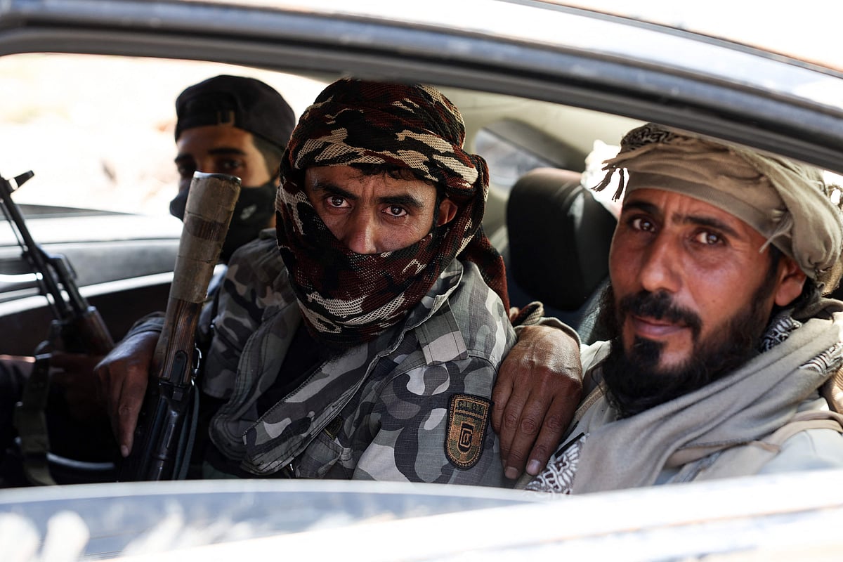 Fighters from Bedouin tribes ride in a car along a road in al-Mazraa village in Syria's southern Sweida governorate, as clashes with Druze gunmen continue on 18 July 2025.