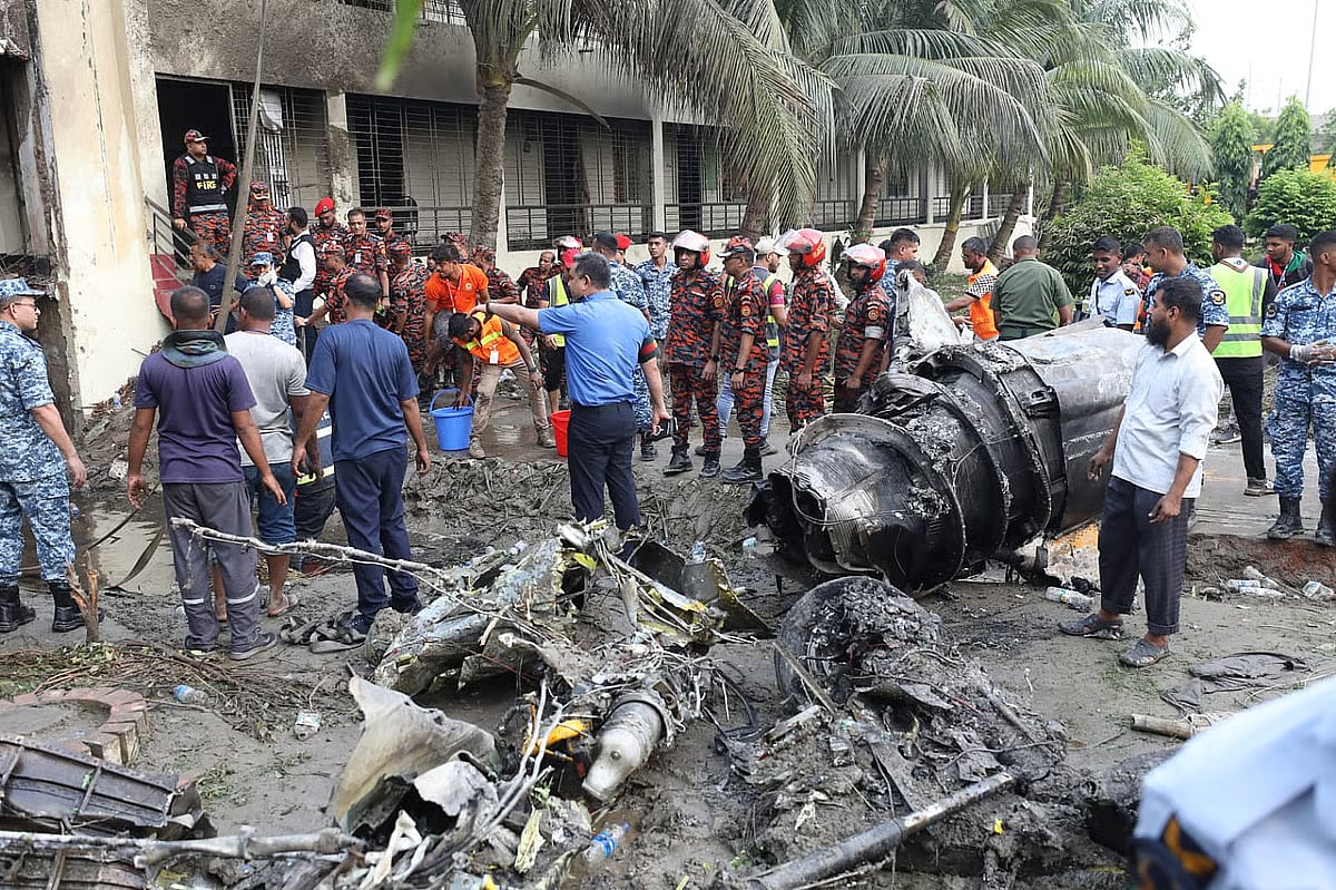 Members of Bangladesh Air Force and other forces look at the crashed aircraft